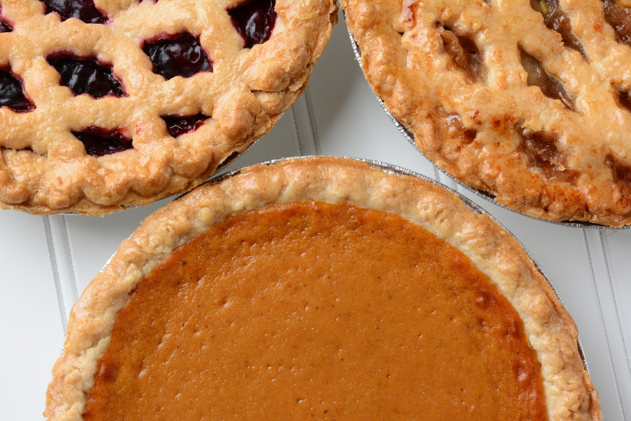 blueberry, pumpkin, and apple pie set on table