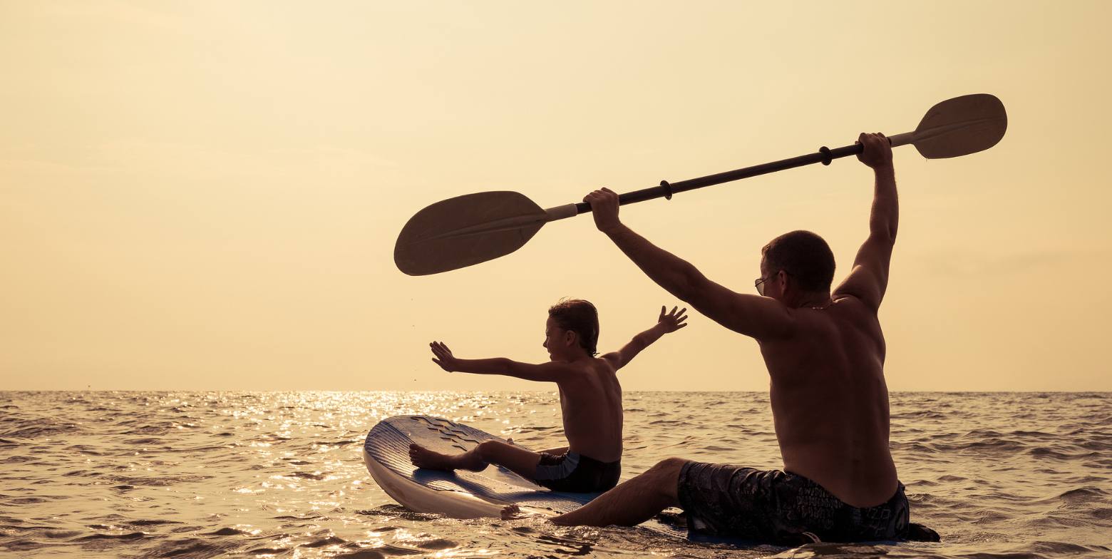 Man and sun on a paddleboard in the ocean at sun set